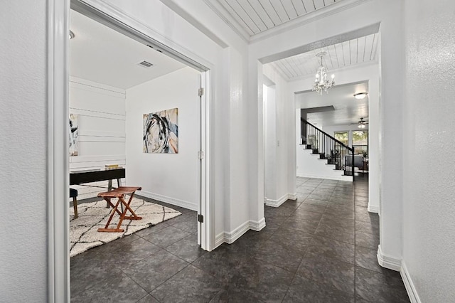 hall with a textured wall, ornamental molding, and baseboards