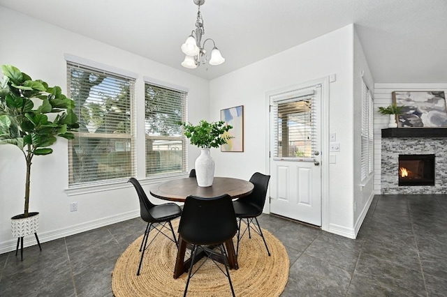 dining space featuring a healthy amount of sunlight, baseboards, a fireplace, and a chandelier