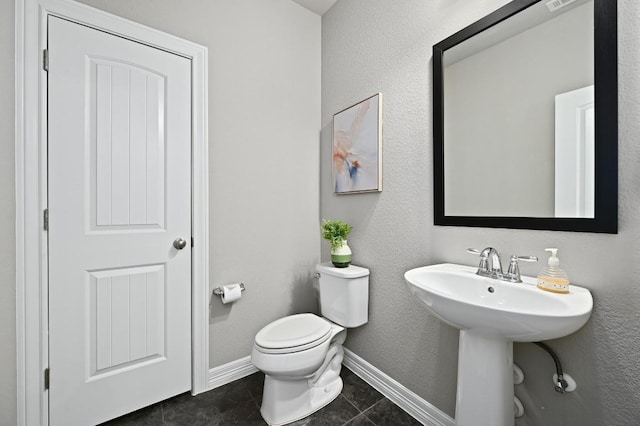 half bath with visible vents, baseboards, toilet, tile patterned floors, and a sink