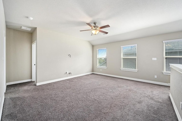 spare room with lofted ceiling, a textured ceiling, a ceiling fan, baseboards, and dark colored carpet