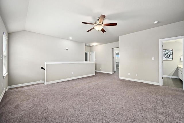 unfurnished room featuring ceiling fan, dark colored carpet, vaulted ceiling, and baseboards