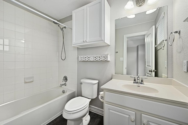 bathroom featuring a textured wall, toilet, vanity,  shower combination, and baseboards