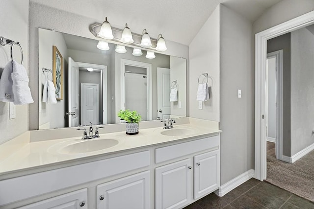 full bathroom with double vanity, baseboards, a sink, and tile patterned floors