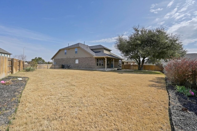 rear view of property featuring a yard, cooling unit, and a fenced backyard