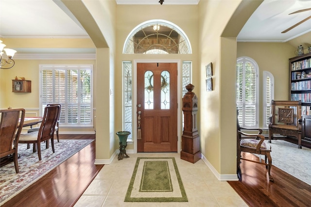 entrance foyer with crown molding, a wealth of natural light, and light tile patterned flooring