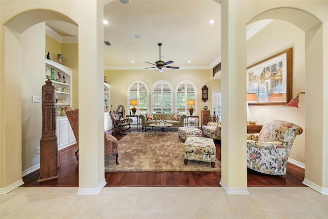 living room with light tile patterned floors, ceiling fan, visible vents, baseboards, and ornamental molding