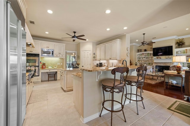 kitchen with visible vents, appliances with stainless steel finishes, open floor plan, a peninsula, and light stone countertops