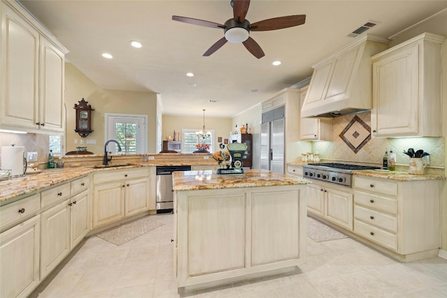 kitchen with a peninsula, appliances with stainless steel finishes, pendant lighting, and light stone counters