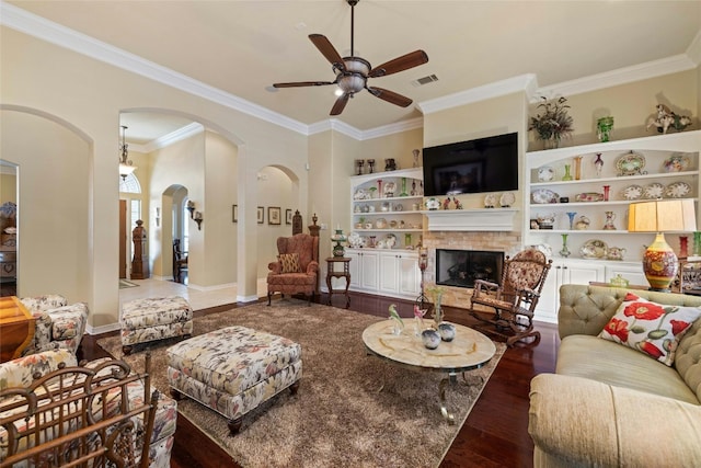 living room featuring visible vents, arched walkways, built in features, dark wood-style floors, and a fireplace