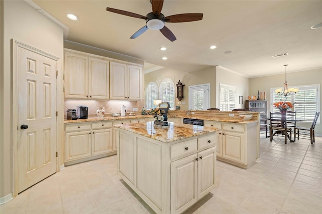 kitchen featuring a peninsula, a center island, light stone countertops, tasteful backsplash, and decorative light fixtures