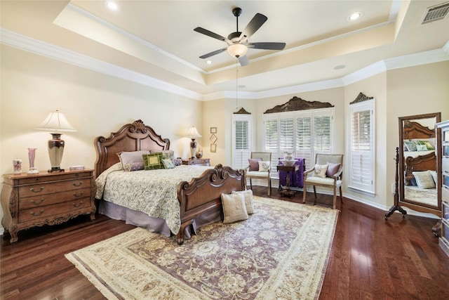 bedroom with a tray ceiling, dark wood-style flooring, and visible vents