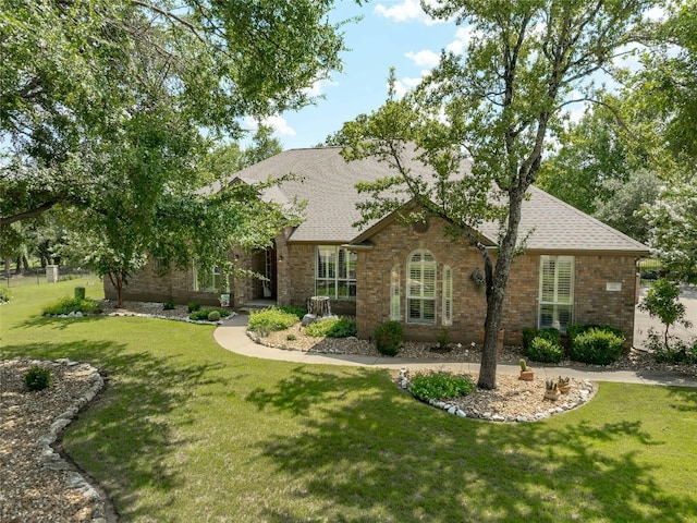 view of front of home with a front lawn, a shingled roof, and brick siding