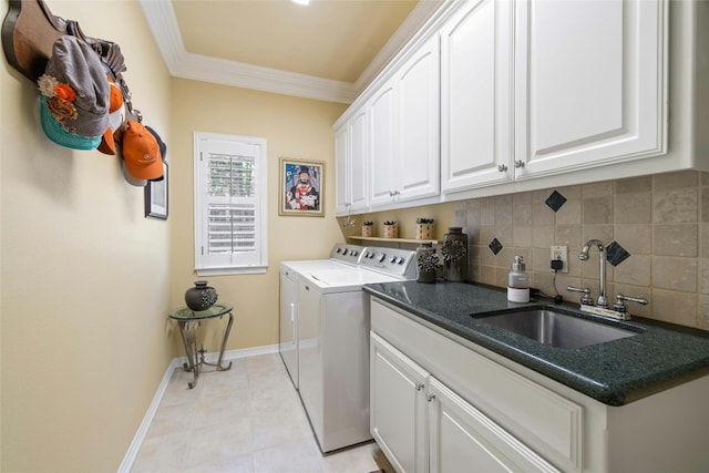 washroom featuring cabinet space, light tile patterned floors, crown molding, washer and dryer, and a sink