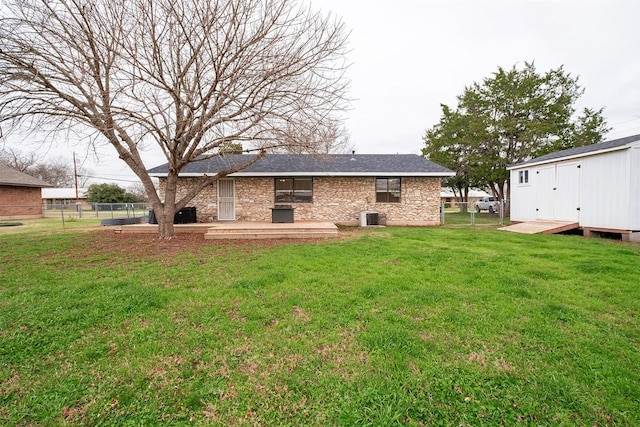 back of property featuring a storage shed, fence, a lawn, and an outdoor structure