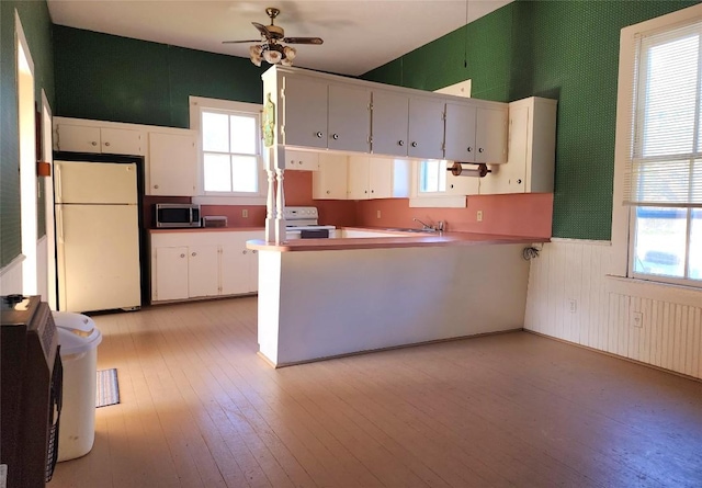 kitchen with a peninsula, white appliances, and white cabinetry