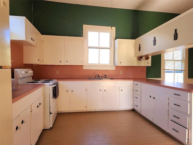 kitchen featuring light countertops, electric stove, white cabinetry, and a healthy amount of sunlight