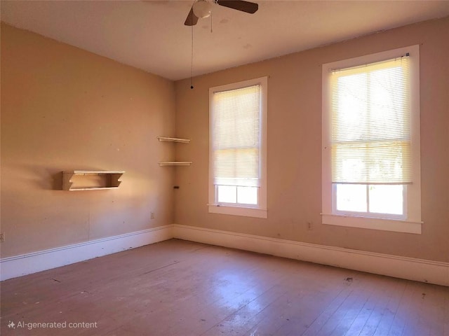 spare room featuring a healthy amount of sunlight, baseboards, and wood finished floors