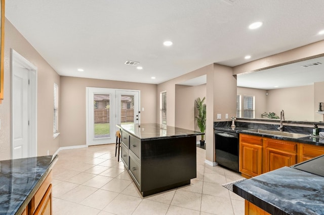 kitchen featuring light tile patterned floors, black dishwasher, visible vents, a center island, and a sink