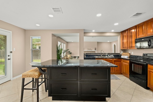 kitchen featuring dark stone counters, black appliances, a kitchen island, and a kitchen breakfast bar