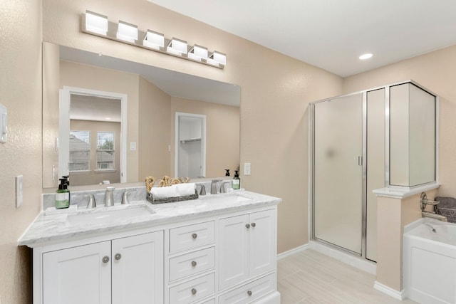 bathroom featuring double vanity, a stall shower, a garden tub, and a sink