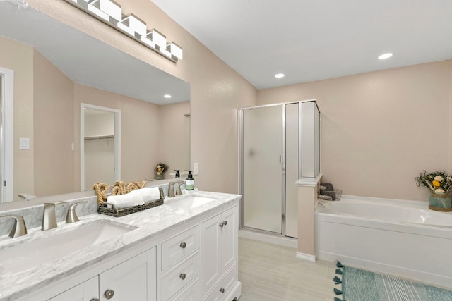 full bathroom with double vanity, a garden tub, a sink, and a stall shower