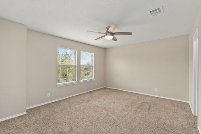 spare room featuring light carpet, baseboards, visible vents, and a ceiling fan