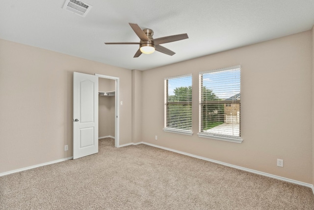 unfurnished room featuring baseboards, visible vents, a ceiling fan, and light colored carpet