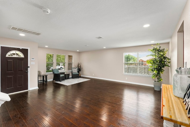 entrance foyer featuring a wealth of natural light, baseboards, visible vents, and dark wood-type flooring