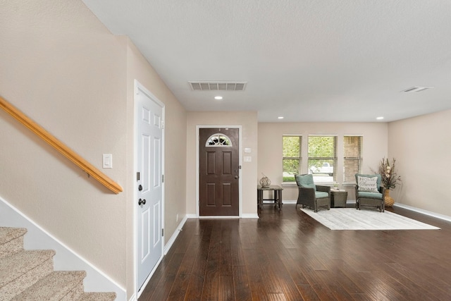 entrance foyer with dark wood-style floors, visible vents, stairway, and baseboards