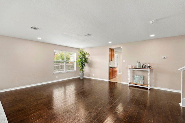 unfurnished living room featuring baseboards, visible vents, dark wood-style flooring, and recessed lighting