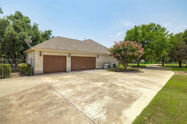 view of property exterior with stone siding, central AC unit, roof with shingles, and fence