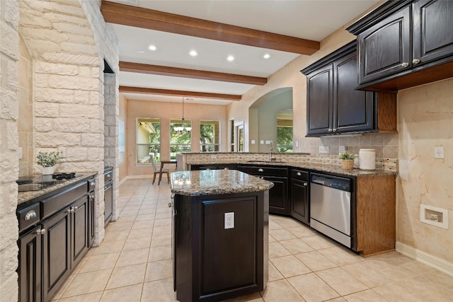 kitchen featuring tasteful backsplash, light stone countertops, beam ceiling, stainless steel dishwasher, and a sink