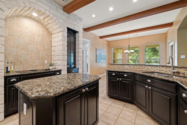 kitchen with dark stone countertops, a kitchen island, and a sink