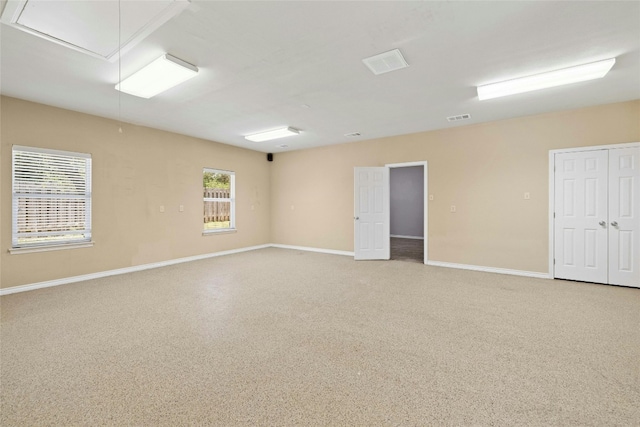 spare room featuring attic access, visible vents, baseboards, and speckled floor