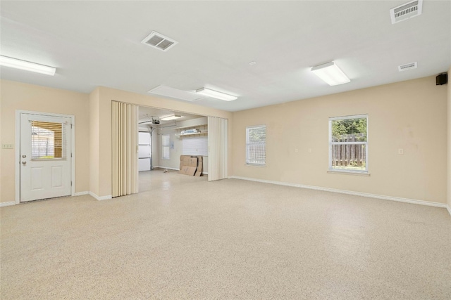 spare room with baseboards, visible vents, and light speckled floor