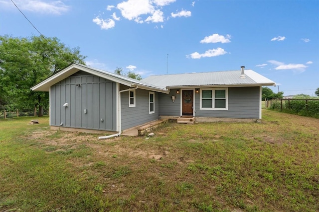 view of front facade with board and batten siding, entry steps, fence, and a front lawn