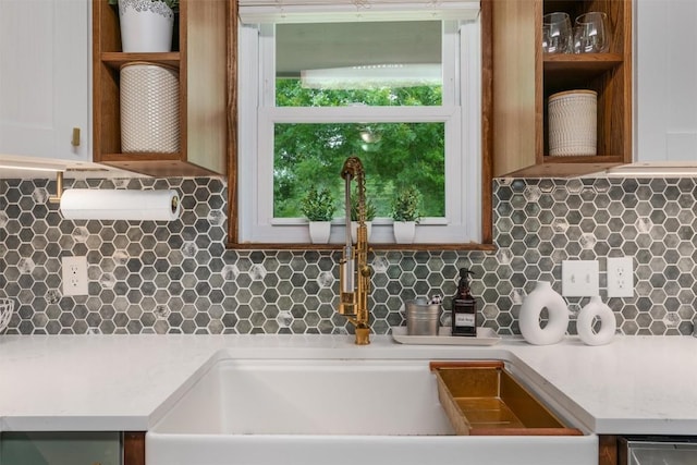 interior details featuring light countertops, a sink, decorative backsplash, and open shelves