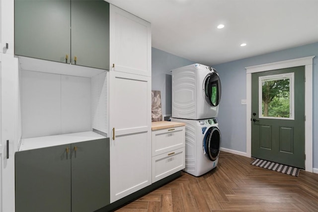 clothes washing area with stacked washer and dryer, recessed lighting, cabinet space, and baseboards