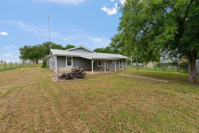 back of house with metal roof, a yard, and fence