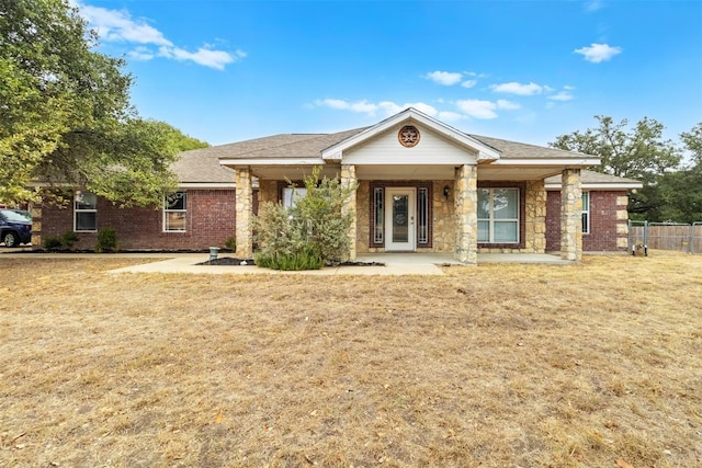 view of front of property with stone siding, a front lawn, fence, and brick siding