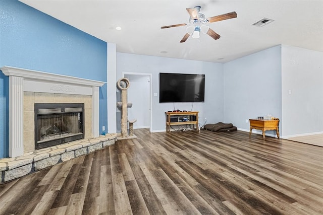 living room with a fireplace with raised hearth, wood finished floors, visible vents, and baseboards