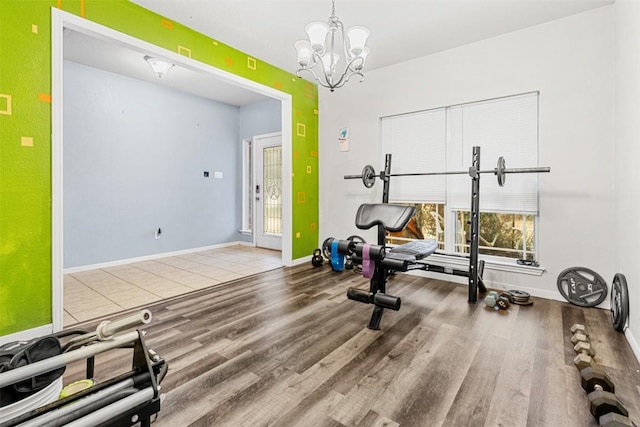 workout area featuring an inviting chandelier, baseboards, and wood finished floors