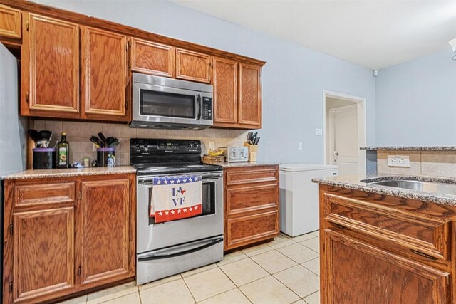 3640 Big Divide Rd, Copperas Cove, TX 76522 - kitchen featuring stainless steel appliances, decorative backsplash, brown cabinetry, light tile patterned floors, and light stone counters