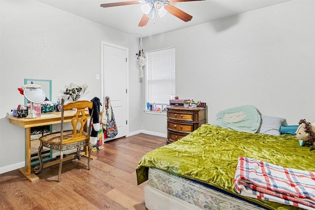 bedroom with ceiling fan, wood finished floors, and baseboards