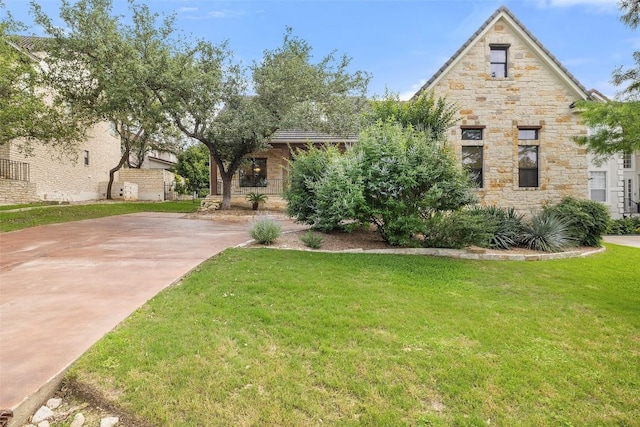 view of front of home with stone siding, concrete driveway, and a front yard