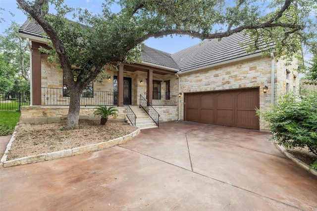 41 Tiburon Dr, The Hills, TX 78738 - view of front of home featuring stone siding, a garage, concrete driveway, and covered porch