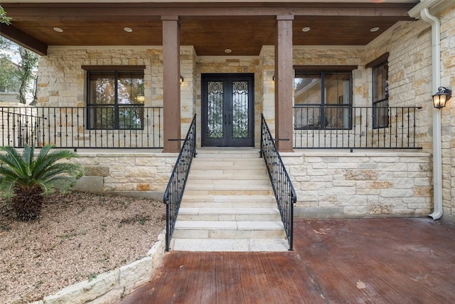 view of exterior entry featuring stone siding and french doors