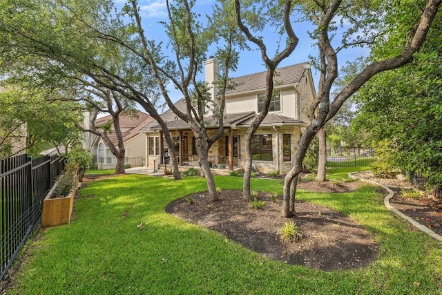 exterior space with a yard, a chimney, stucco siding, stone siding, and a fenced backyard