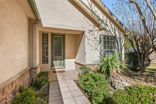 view of exterior entry with a patio and stucco siding