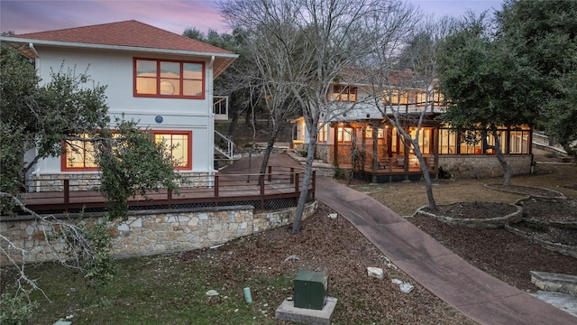 5242 Mccormick Mountain Dr Unit E, Austin, TX 78734 - back of property at dusk with a wooden deck, a sunroom, stucco siding, and roof with shingles